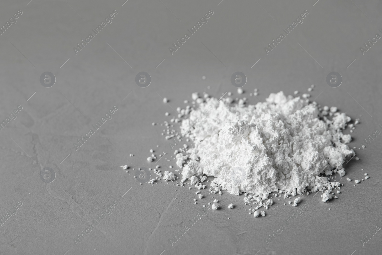 Photo of Heap of calcium carbonate powder on grey table. Space for text