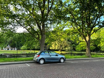 Modern car parked near lake on sunny day