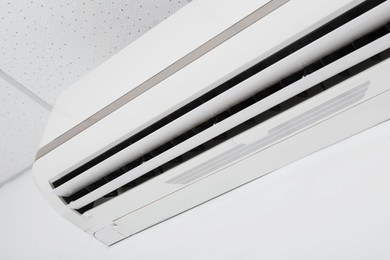 Photo of Modern air conditioner on white wall, closeup