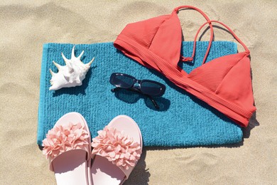 Photo of Towel, flip flops and bra on sand, top view. Beach accessories