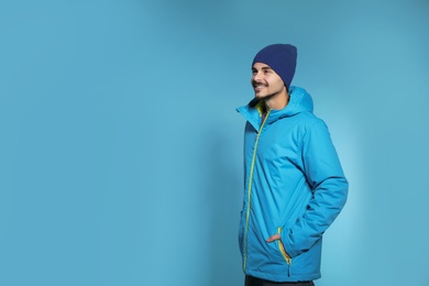 Photo of Young man wearing warm clothes on color background, space for text. Ready for winter vacation
