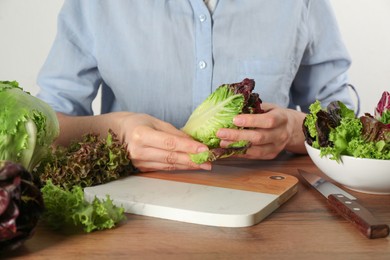 Photo of Woman with red romaine lettuce at wooden table, closeup