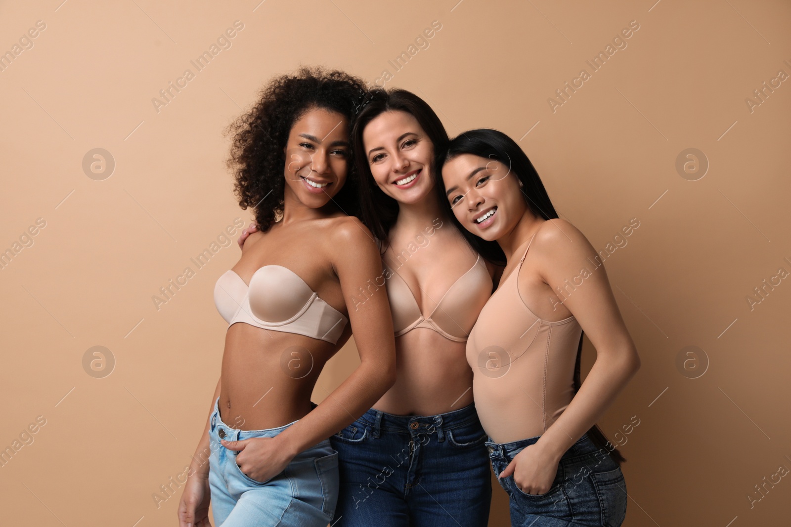 Photo of Group of women with different body types in jeans and underwear on beige background