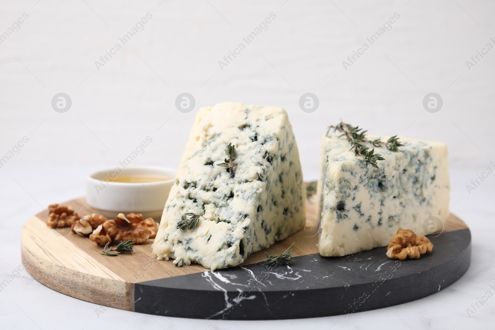 Photo of Tasty blue cheese with thyme, honey and walnuts on white marble table