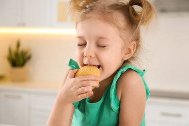 Cute little girl eating cookies in kitchen