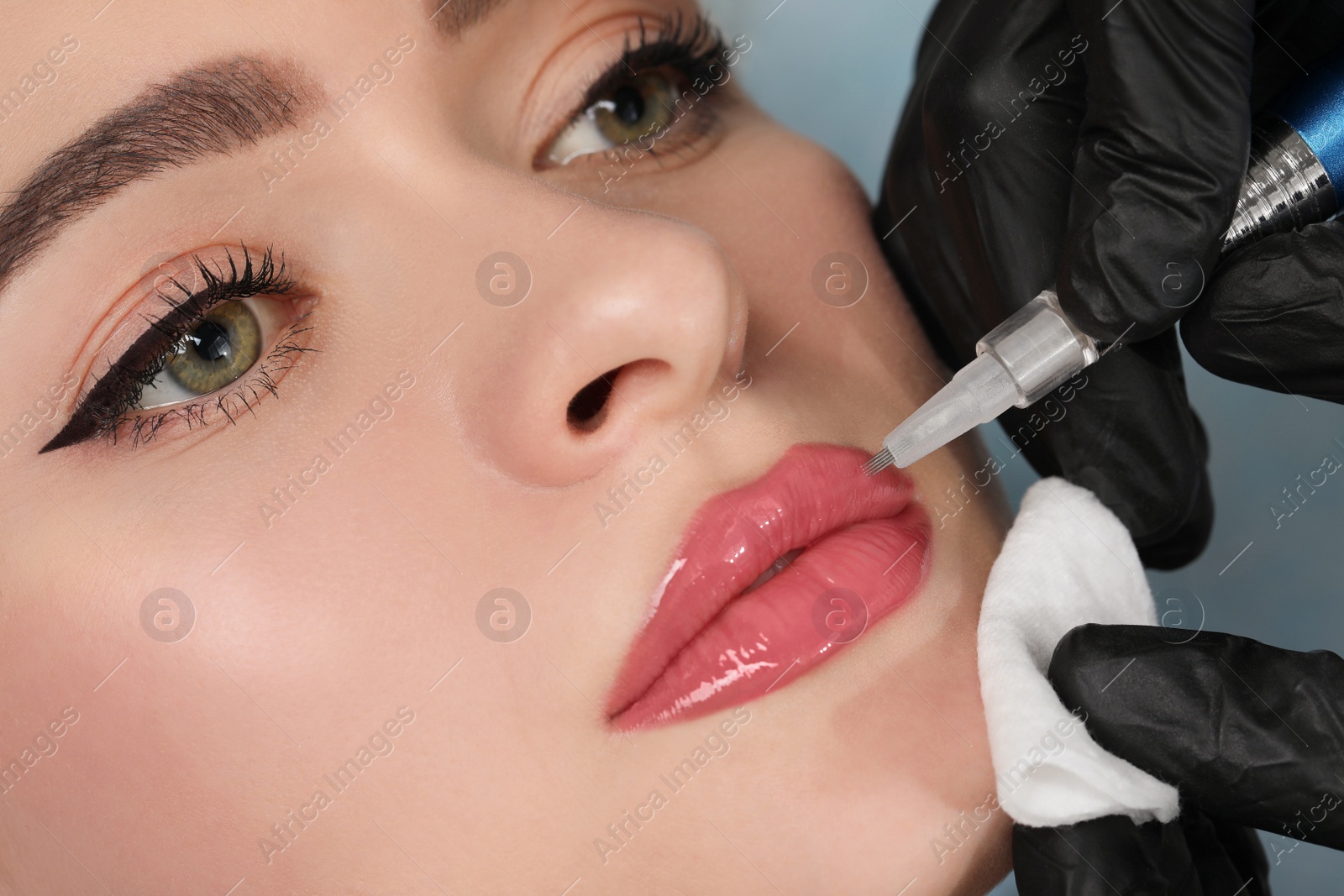 Photo of Young woman during procedure of permanent lip makeup in beauty salon, closeup