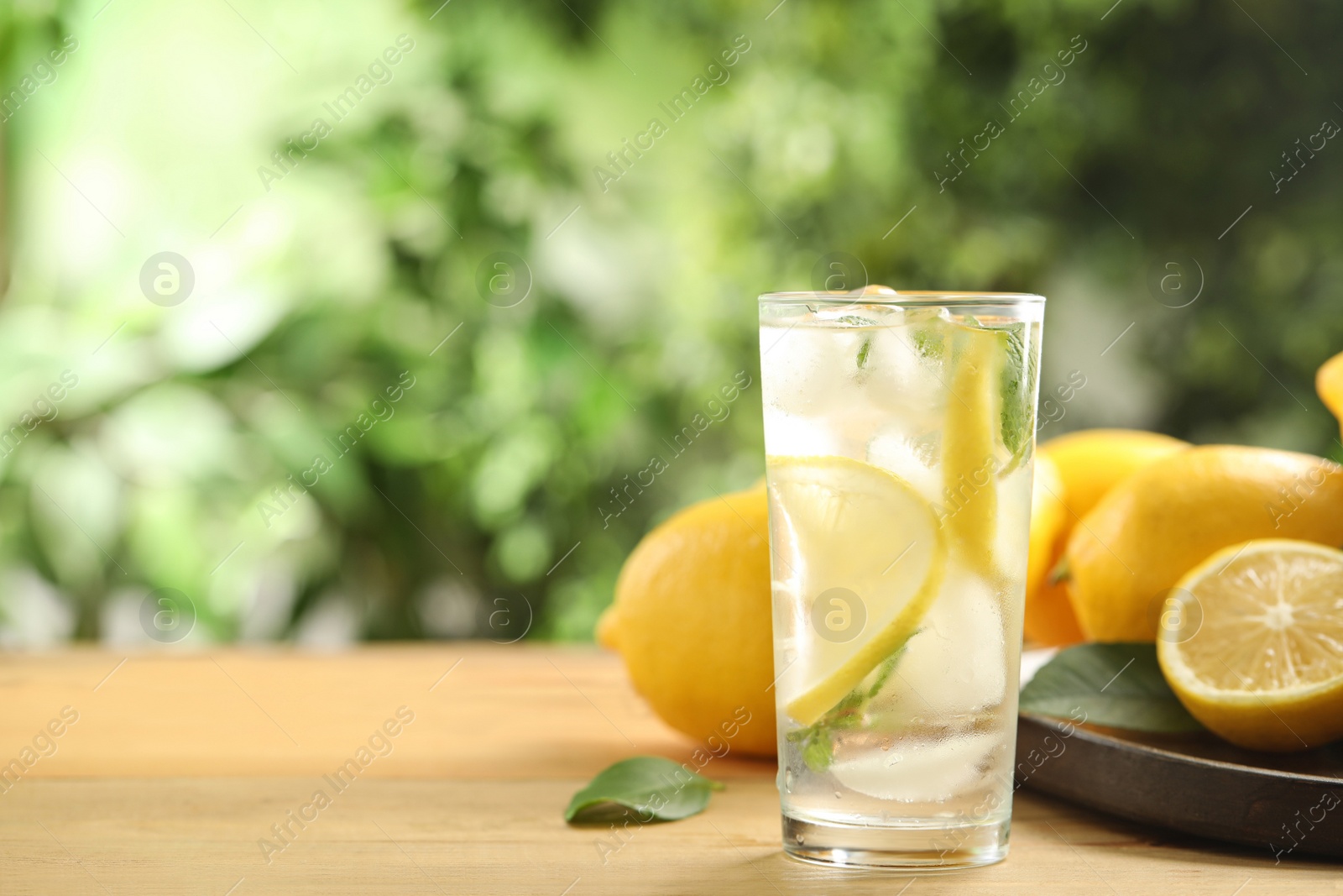 Photo of Cool freshly made lemonade and fruits on wooden table. Space for text