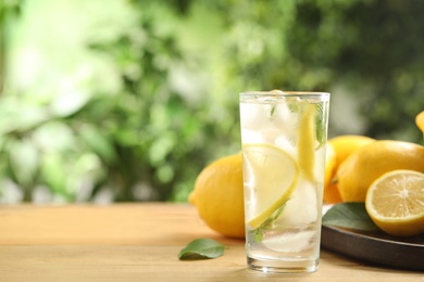 Photo of Cool freshly made lemonade and fruits on wooden table. Space for text