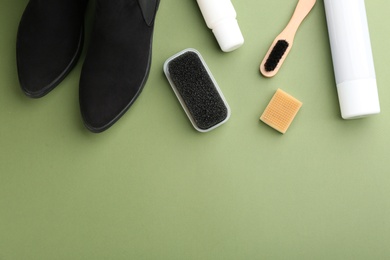 Photo of Stylish footwear with shoe care accessories on green background, flat lay. Space for text
