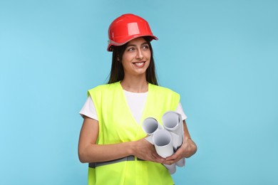 Architect in hard hat with drafts on light blue background