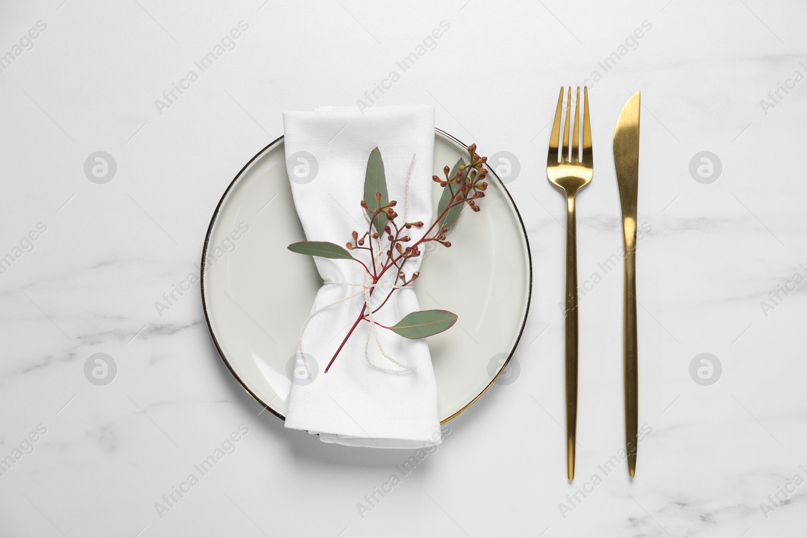 Photo of Stylish setting with cutlery and eucalyptus leaves on white marble table, flat lay