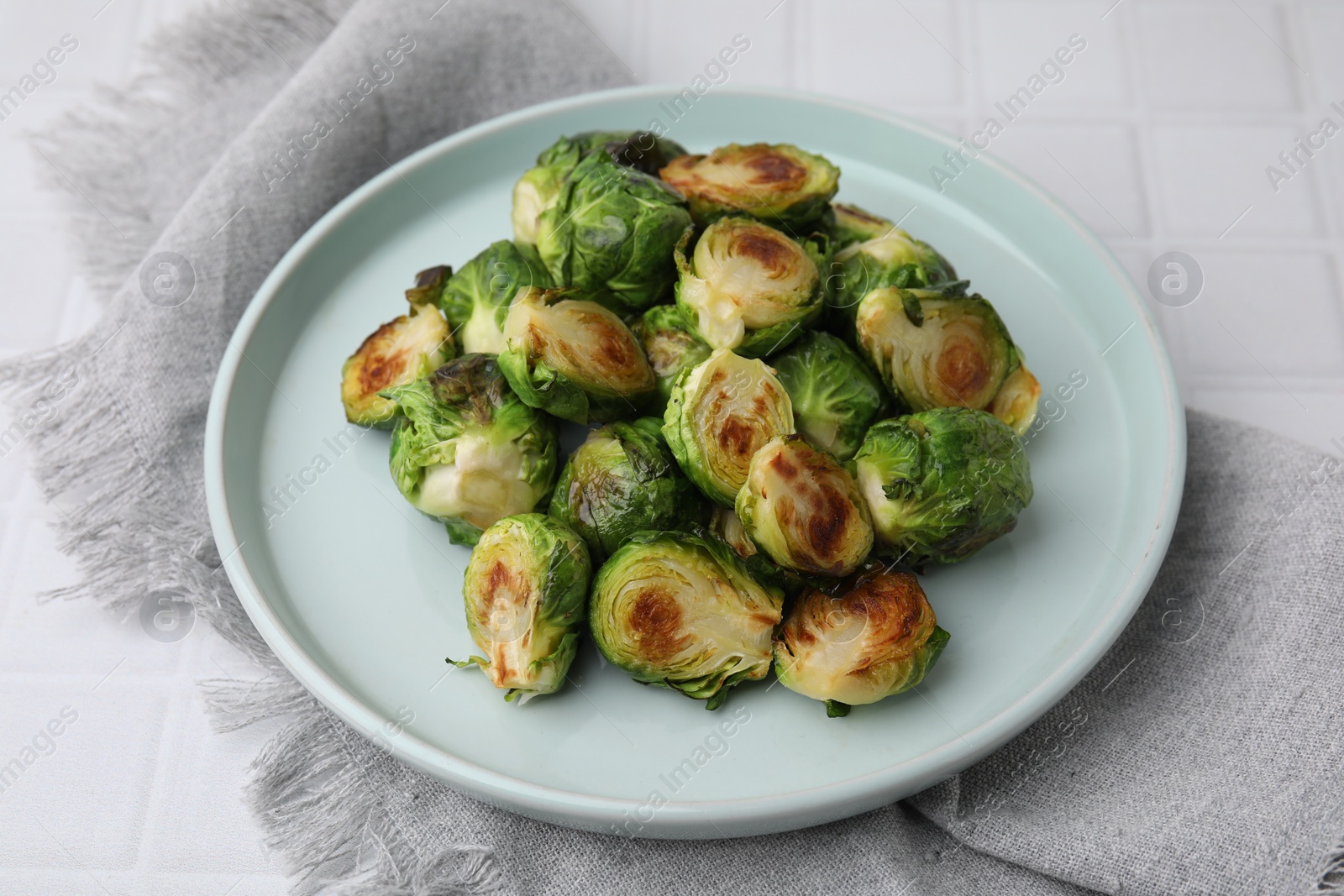 Photo of Delicious roasted Brussels sprouts on white tiled table