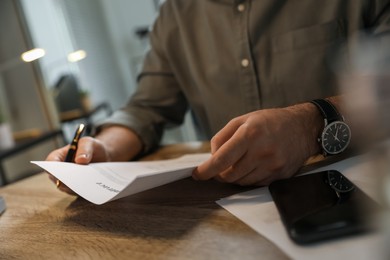 Photo of Businessman working with documents at wooden desk in office, closeup