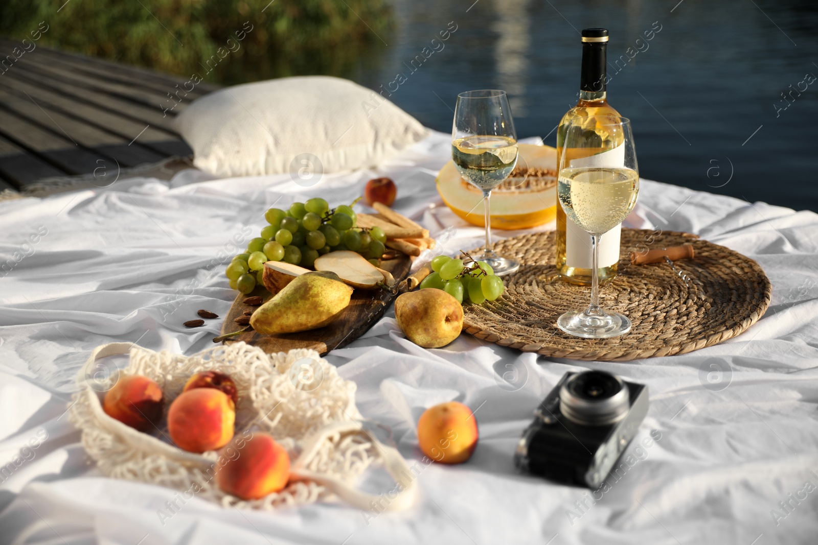 Photo of Picnic blanket with delicious food and wine on pier