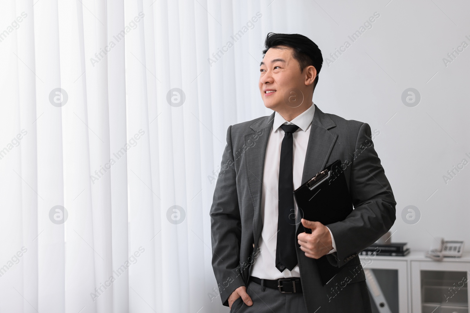 Photo of Portrait of happy notary with clipboard indoors, space for text