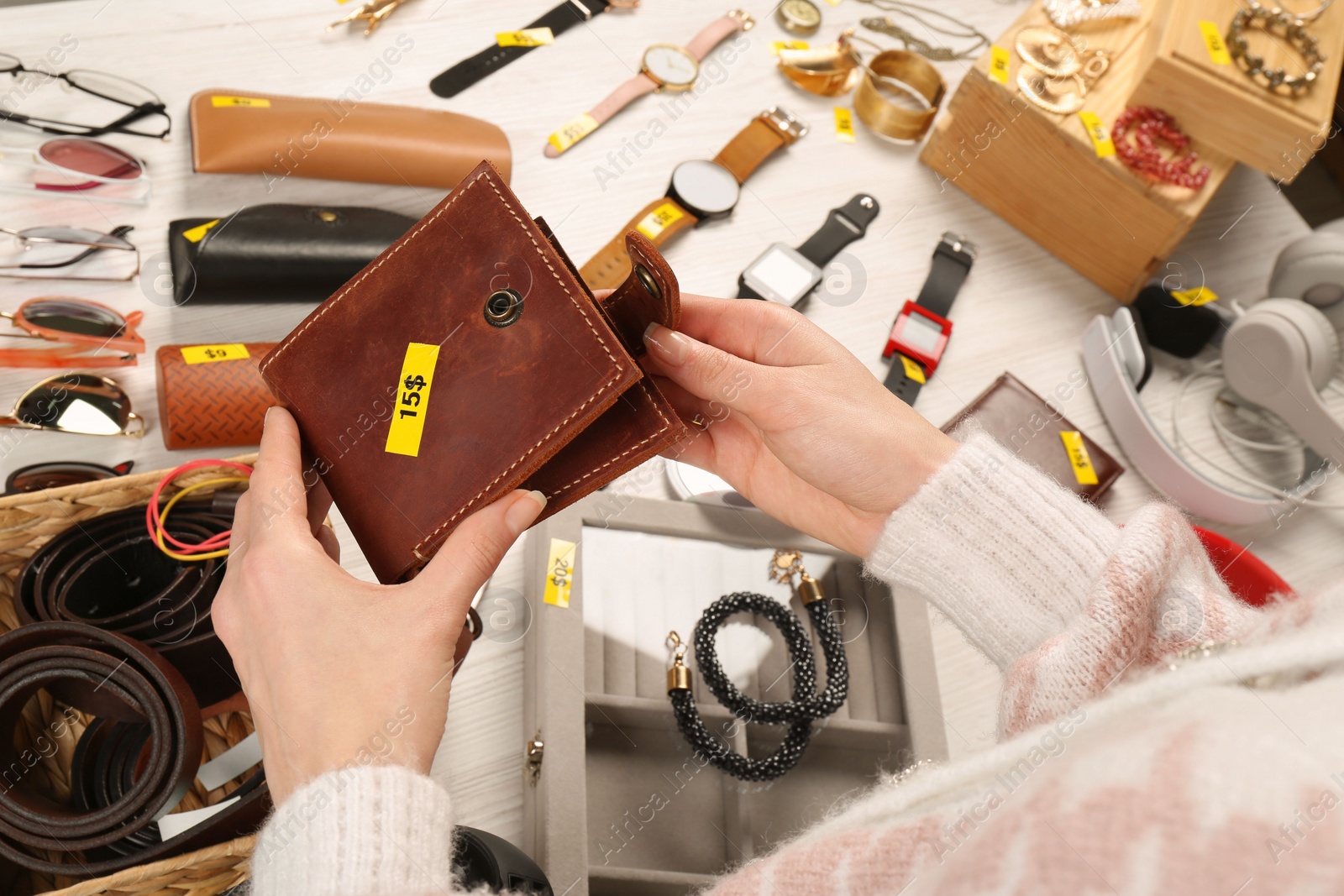 Photo of Woman holding wallet near table with different stuff, closeup. Garage sale