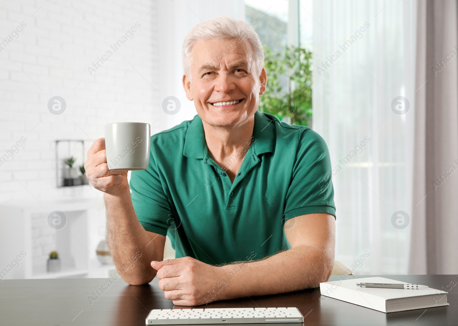 Photo of Mature man with drink using video chat at home, view from web camera