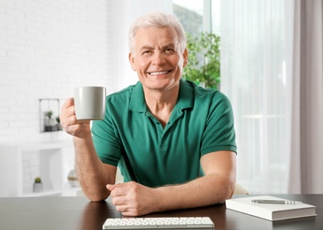 Mature man with drink using video chat at home, view from web camera