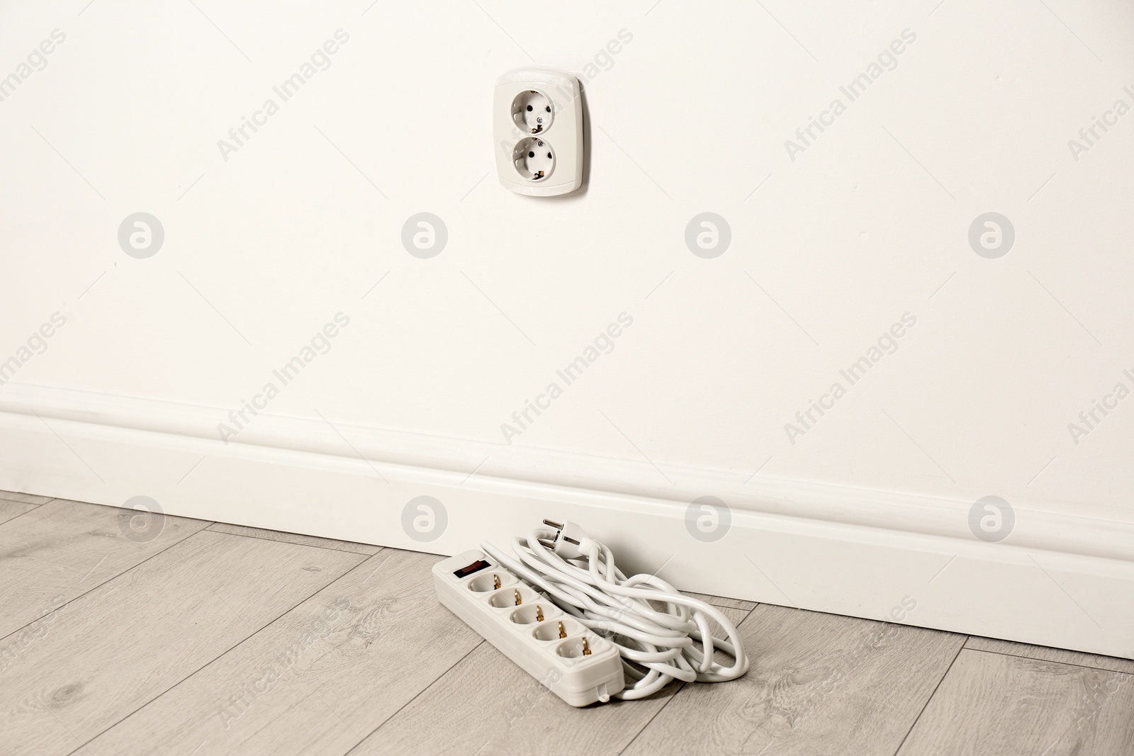 Photo of Extension cord near wall indoors, space for text. Electrician's professional equipment