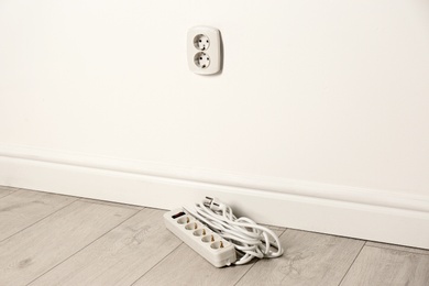 Photo of Extension cord near wall indoors, space for text. Electrician's professional equipment