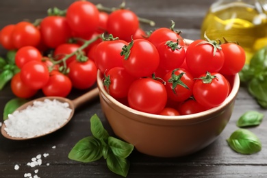 Photo of Fresh cherry tomatoes, basil and sea salt on wooden table