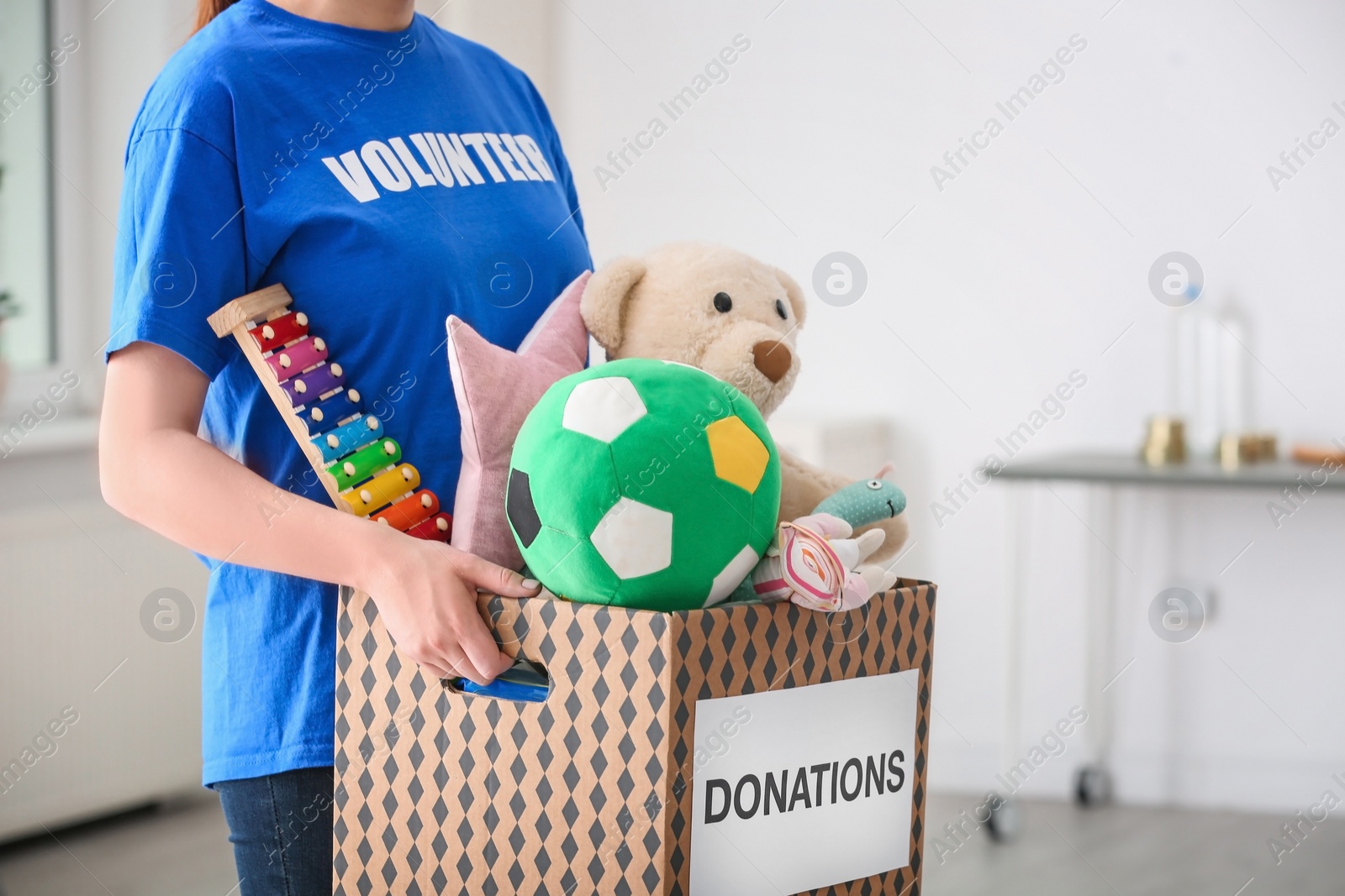 Photo of Female volunteer holding donation box with toys indoors