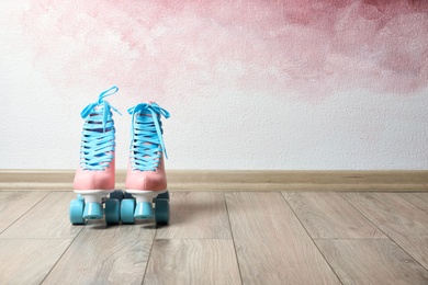 Vintage roller skates on floor near color wall. Space for text