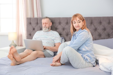 Mature couple with problem in relationship on bed at home