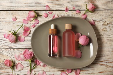 Photo of Flat lay composition with essential rose oil and flowers on white wooden table