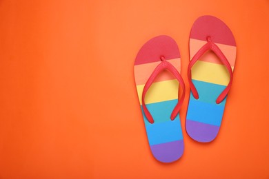 Photo of Rainbow flip flops on orange background, flat lay with space for text. LGBT pride