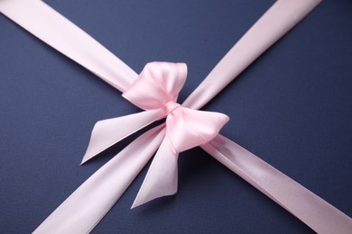 Photo of Pink satin ribbon with bow on blue background