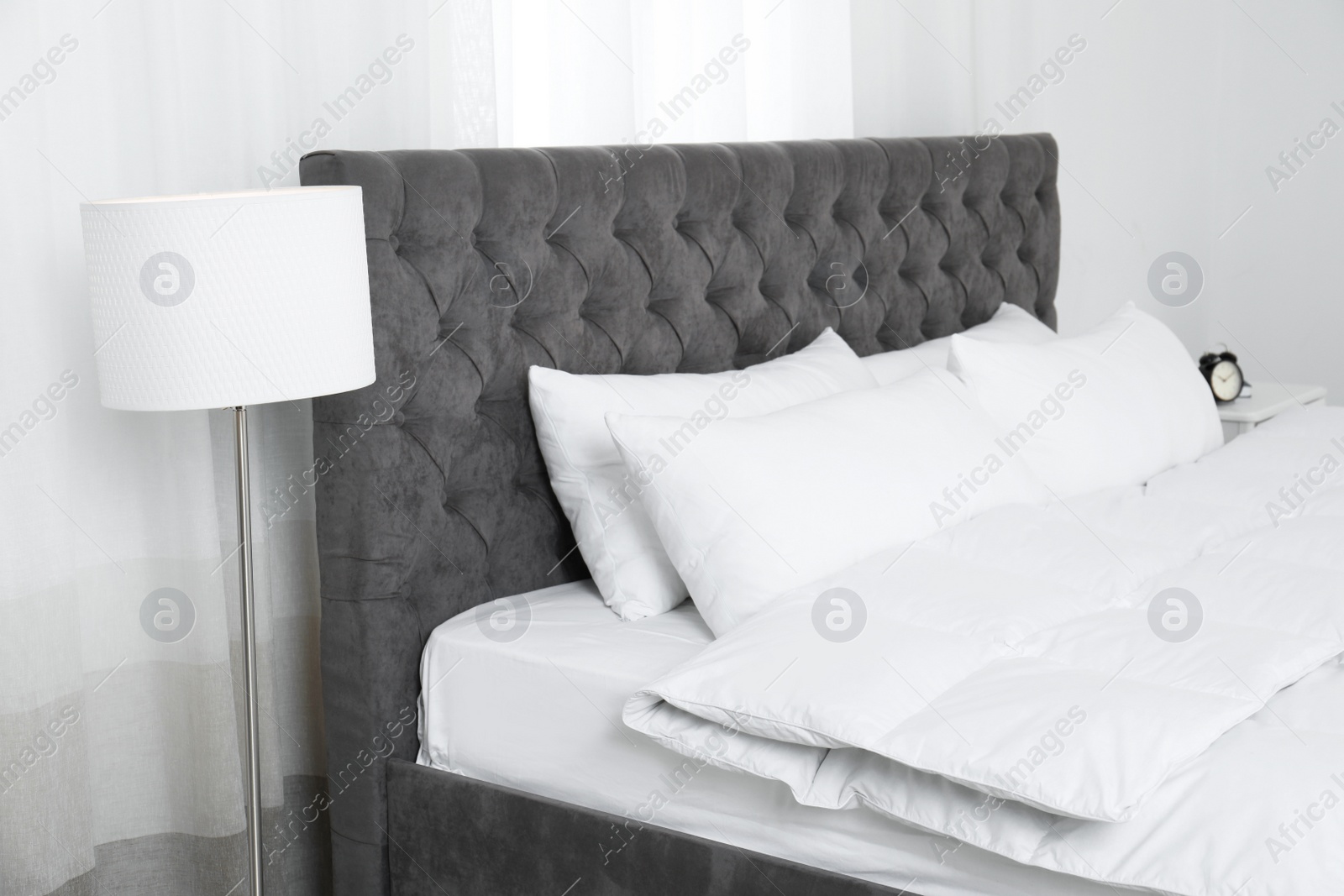 Photo of Large comfortable bed in light room. Stylish interior