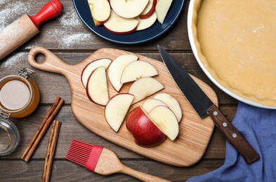 Cut fresh apple with knife and board on wooden table, flat lay. Baking pie