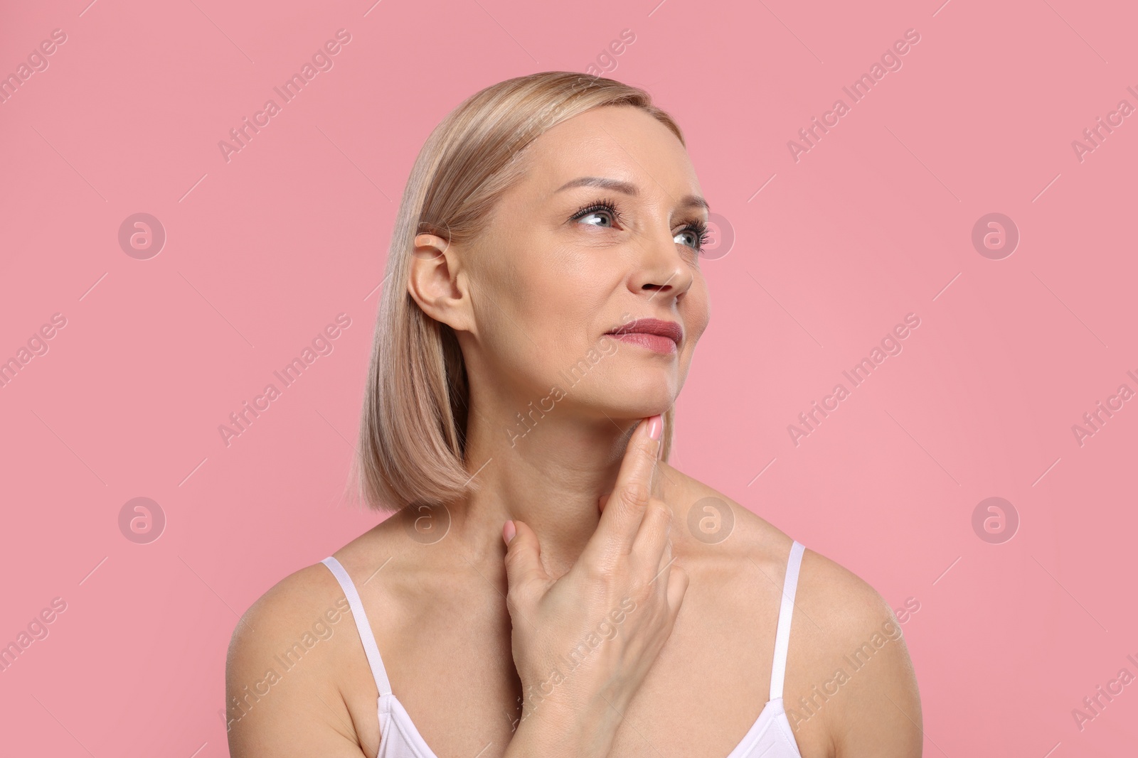 Photo of Beautiful woman touching her neck on pink background