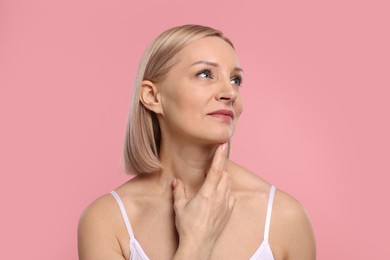 Photo of Beautiful woman touching her neck on pink background