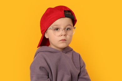 Cute little boy in glasses on orange background