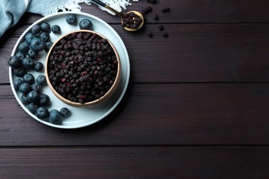 Photo of Freeze dried and fresh blueberries on wooden table, flat lay. Space for text