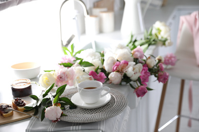 Photo of Beautiful peonies and breakfast on kitchen counter