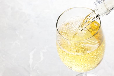 Pouring tasty aromatic wine in glass at gray marble table, closeup. Space for text