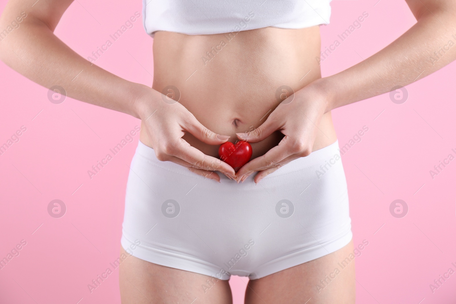 Photo of Young woman holding heart near underwear on color background. Gynecology