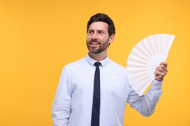 Photo of Happy man holding hand fan on orange background