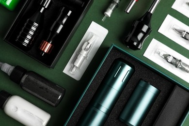 Flat lay composition with tattoo equipment on dark green background