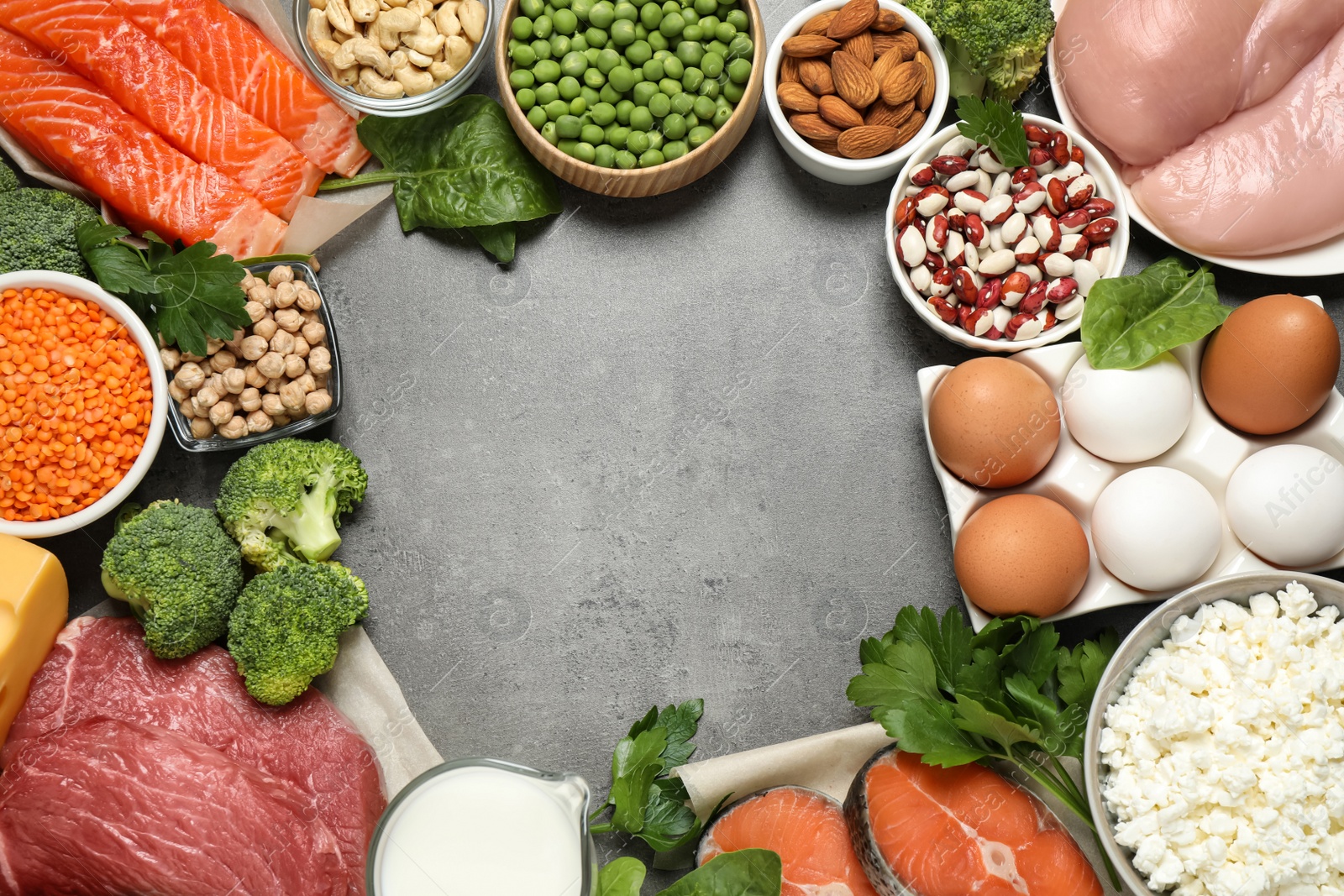 Photo of Frame of products rich in protein on grey table, flat lay. Space for text