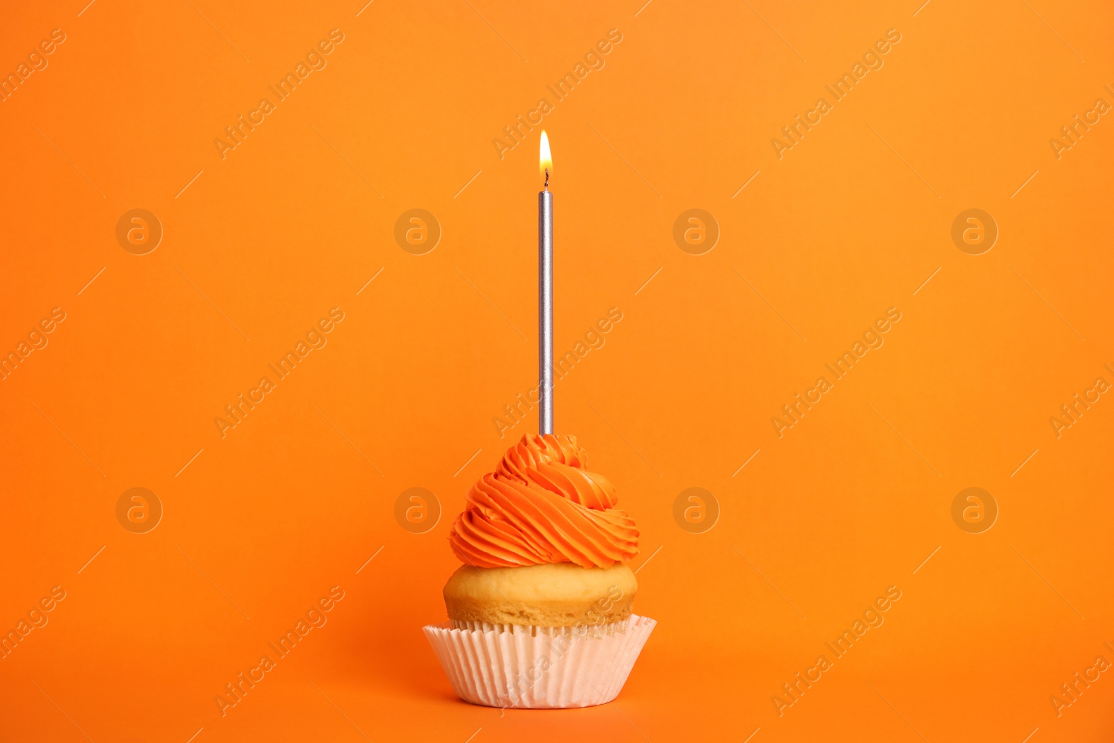Photo of Birthday cupcake with candle on orange background