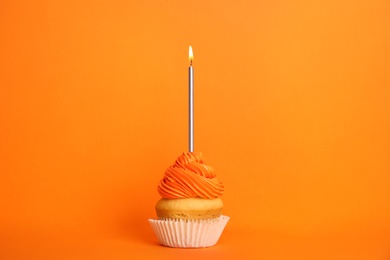 Photo of Birthday cupcake with candle on orange background