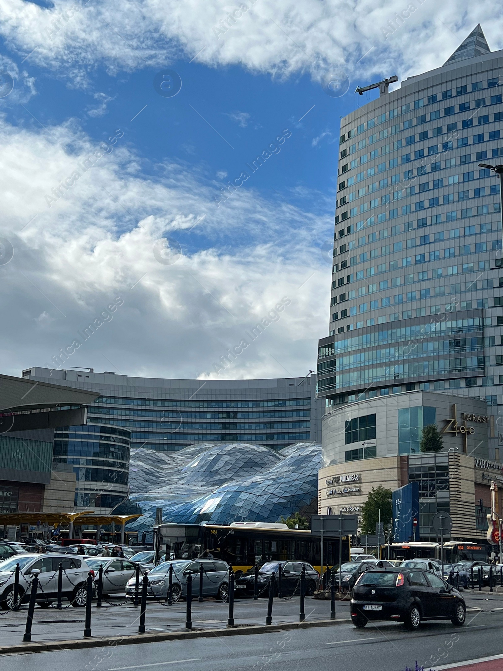 Photo of WARSAW, POLAND - JULY 17, 2022: View of shopping mall and parked cars under cloudy sky