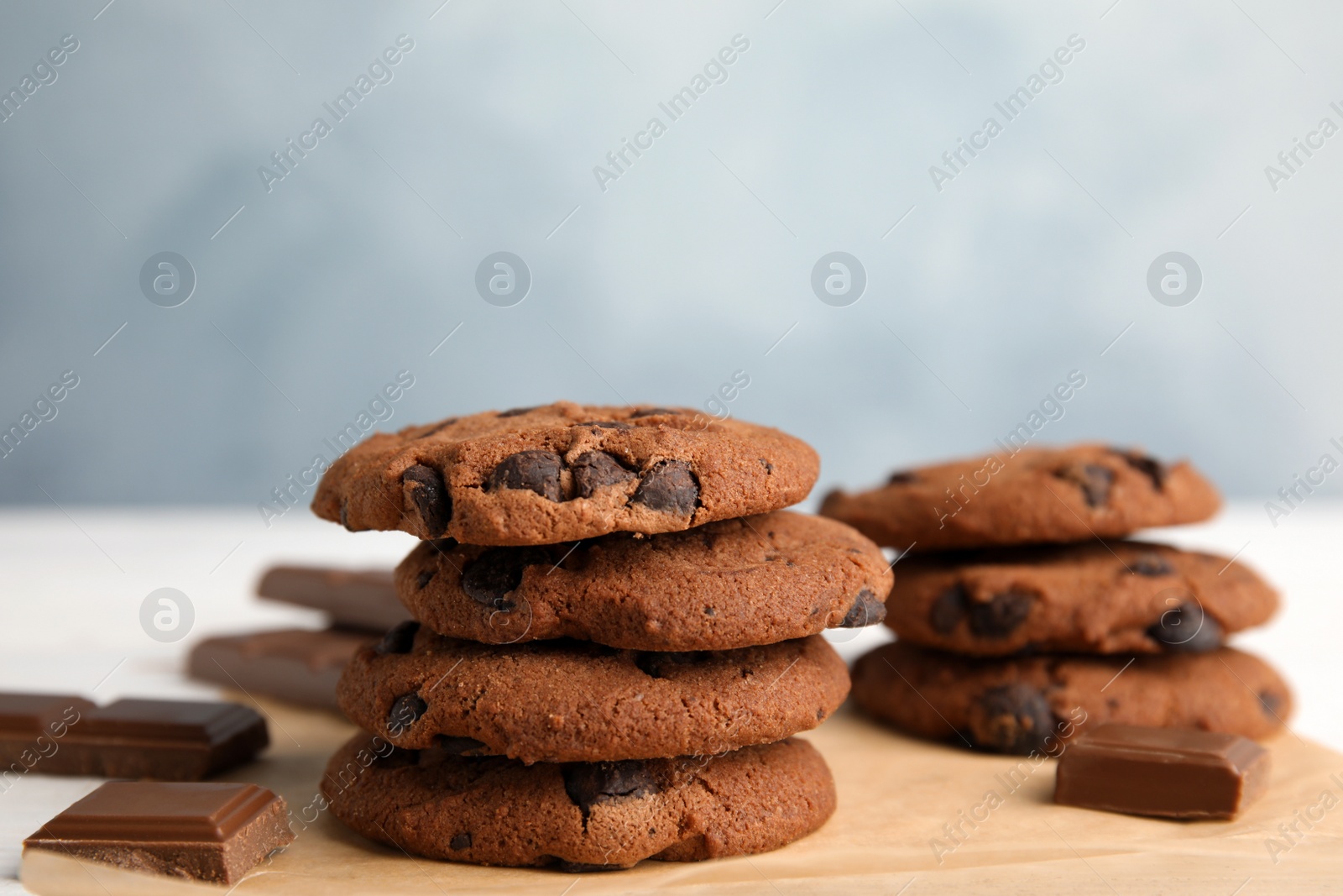 Photo of Stack of tasty chocolate chip cookies on parchment, closeup