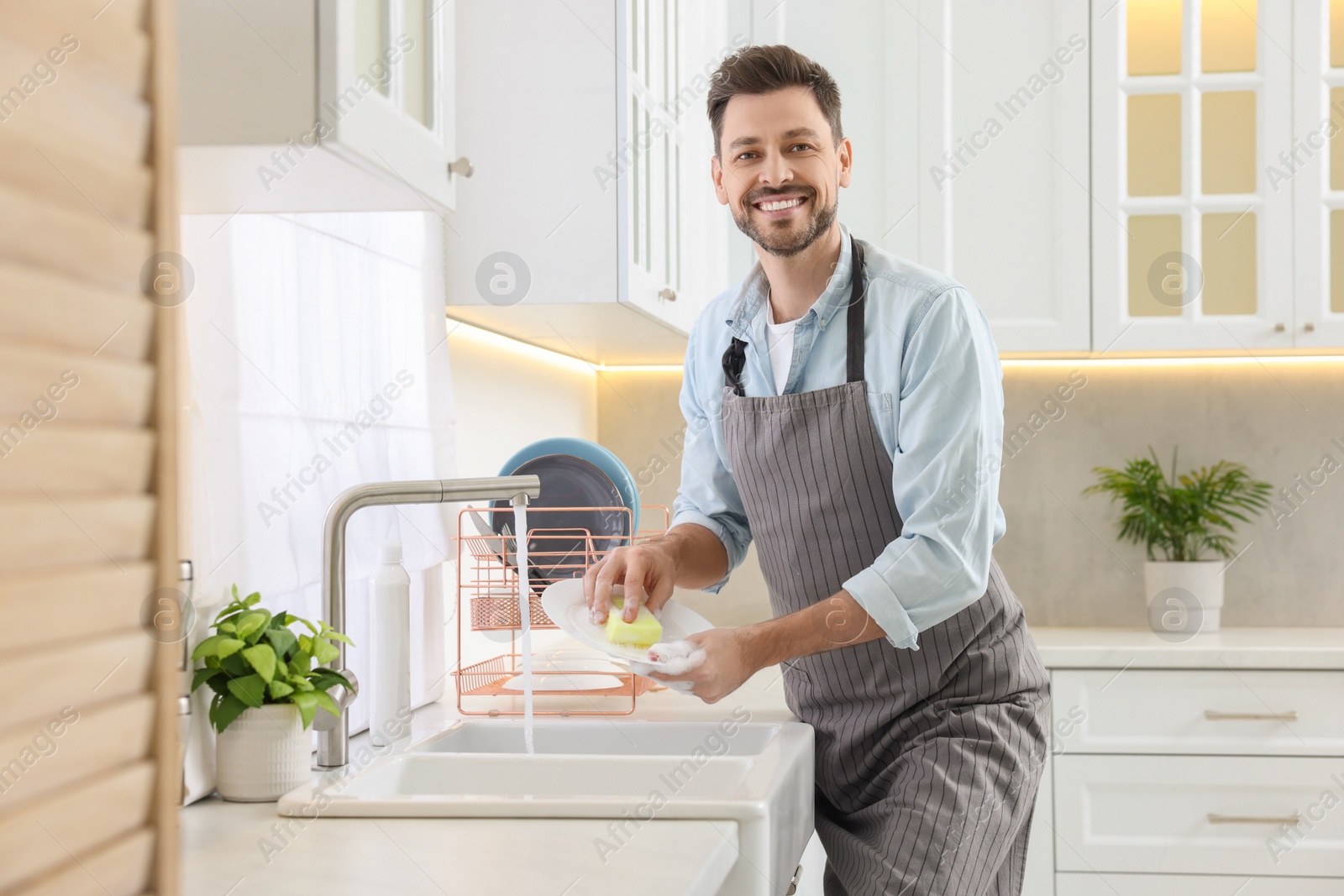 Photo of Man washing plate above sink in kitchen