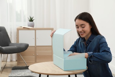 Photo of Happy young woman with parcel at home. Internet shopping