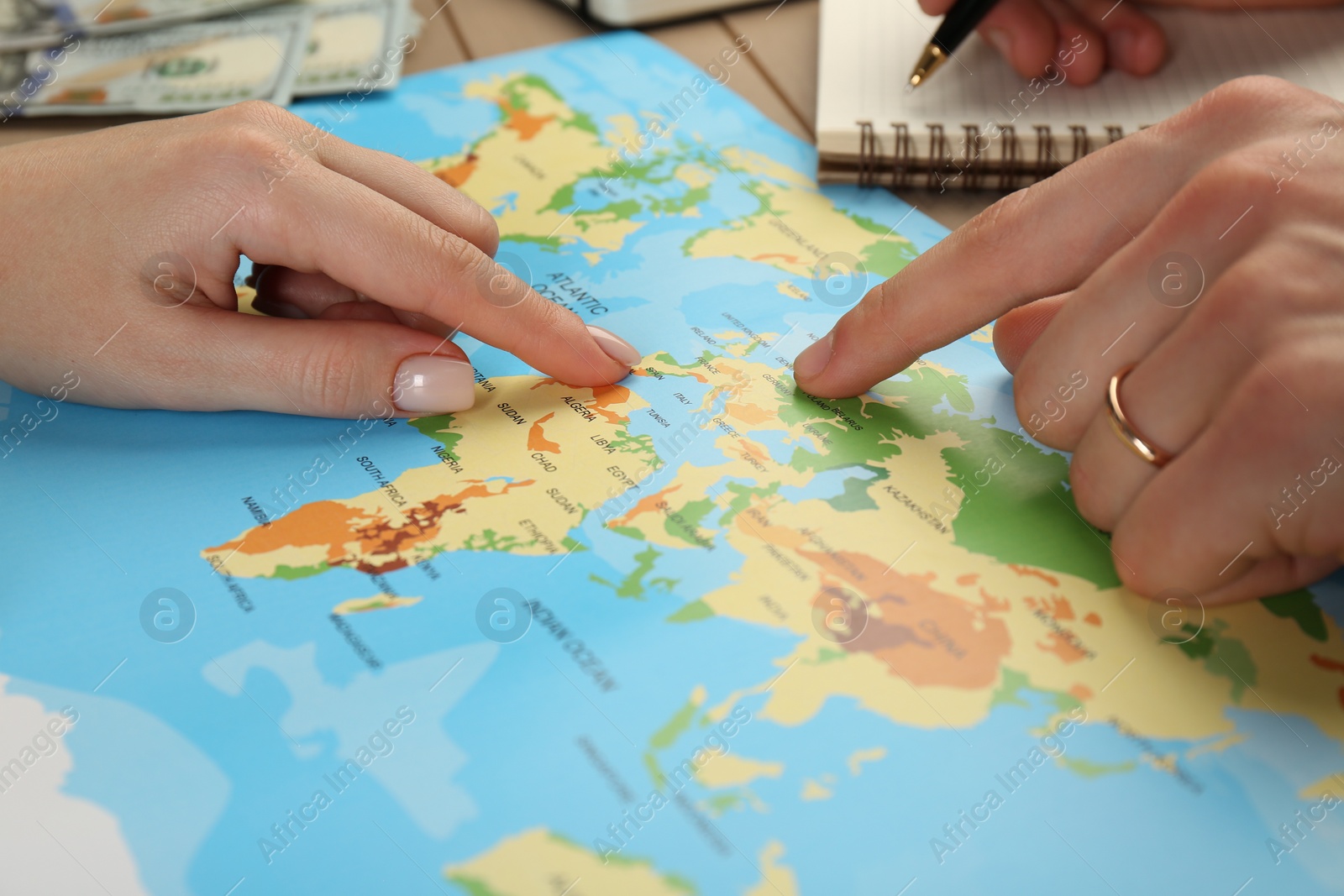 Photo of Man and woman planning their honeymoon trip with world map at table, closeup